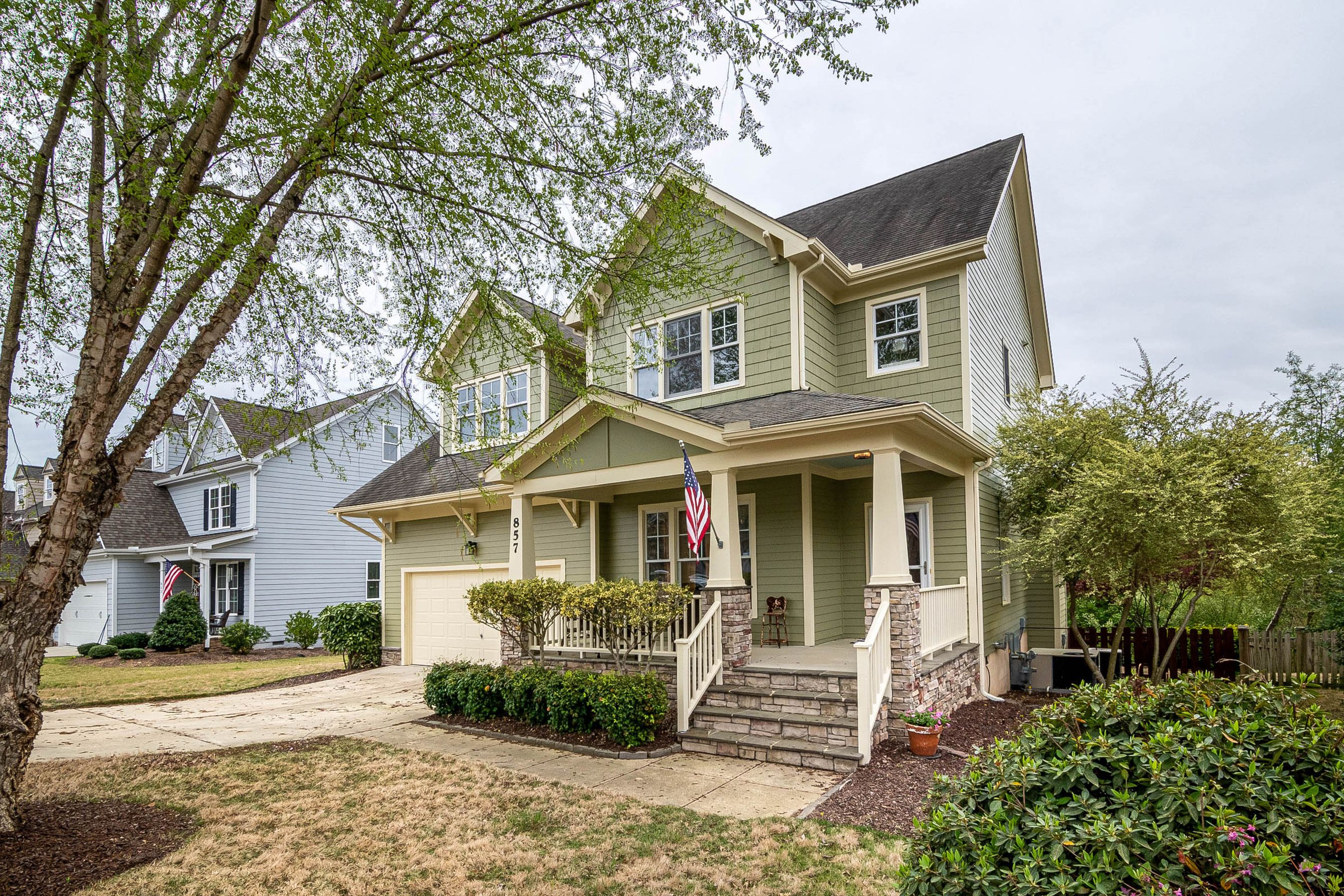 A green craftsman-style two-story house with a covered front porch.